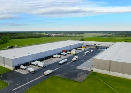 Aerial Shot of Industrial Warehouse/ Storage Building/ Loading Area where Many Trucks Are Loading/ Unloading Merchandise.